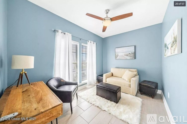 A living room with a ceiling fan and a light blue wall.