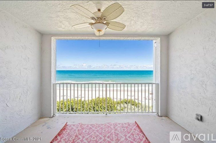 A balcony with a red carpet leads to a beach.
