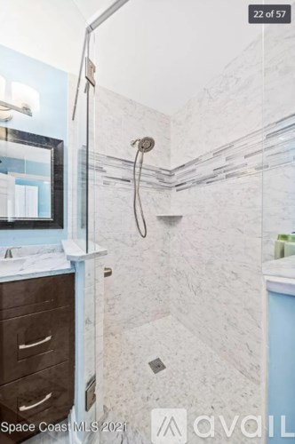 A bathroom with a walk-in shower and a vanity with a mirror.