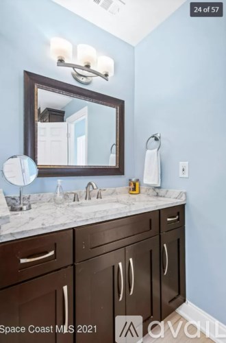 A bathroom with brown cabinets and a marble countertop.