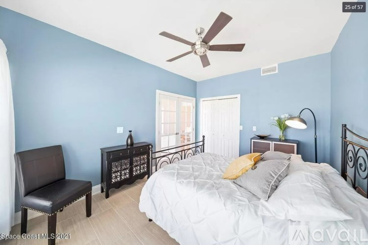 A bedroom with a bed, chair, and nightstand.
