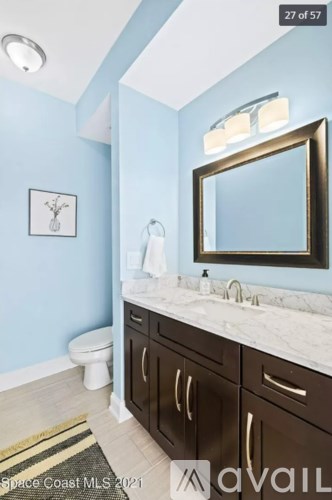 A bathroom with a toilet, sink, and a mirror.