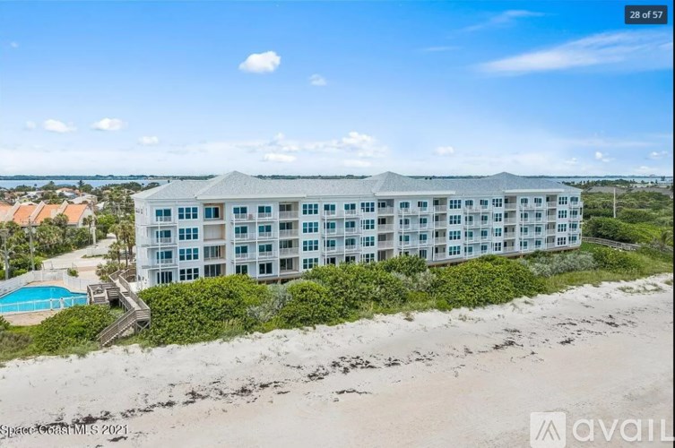 A beachfront building with a pool and a clear sky.