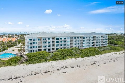 A beachfront building with a pool and a clear sky.