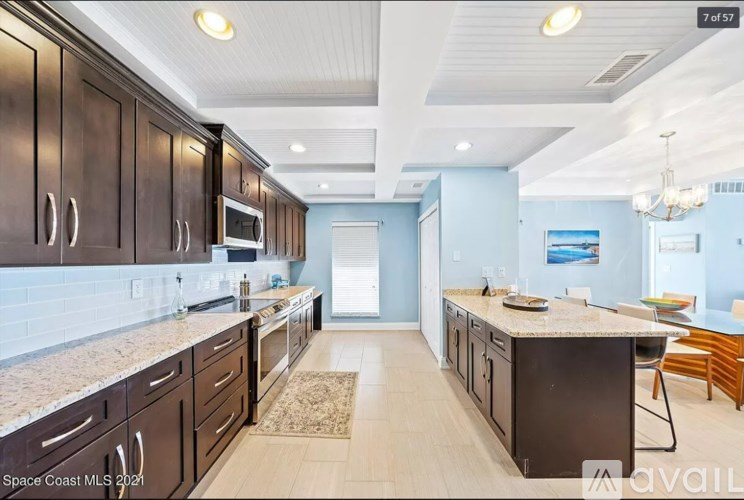 A kitchen with dark brown cabinets and a granite countertop.