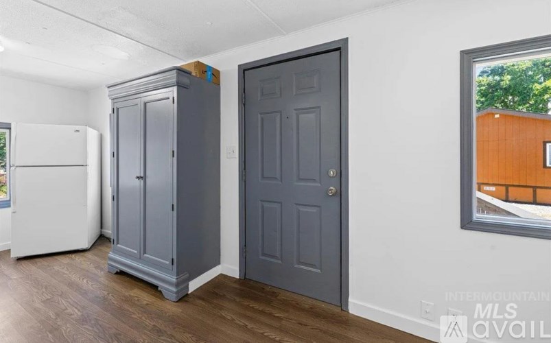 A kitchen with a white fridge, a grey door and a grey cupboard.