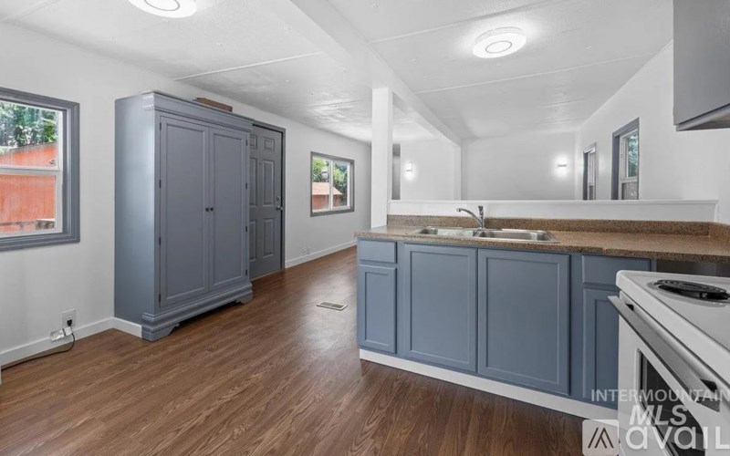 A kitchen with wooden floors and grey cabinets.