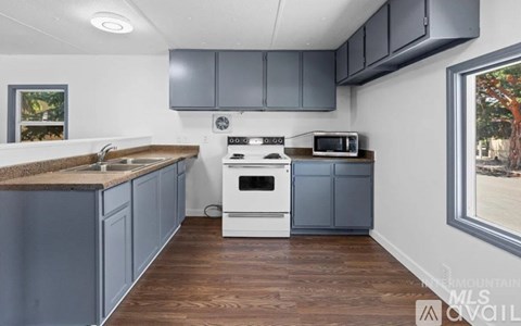 A kitchen with a white stove and grey cabinets.
