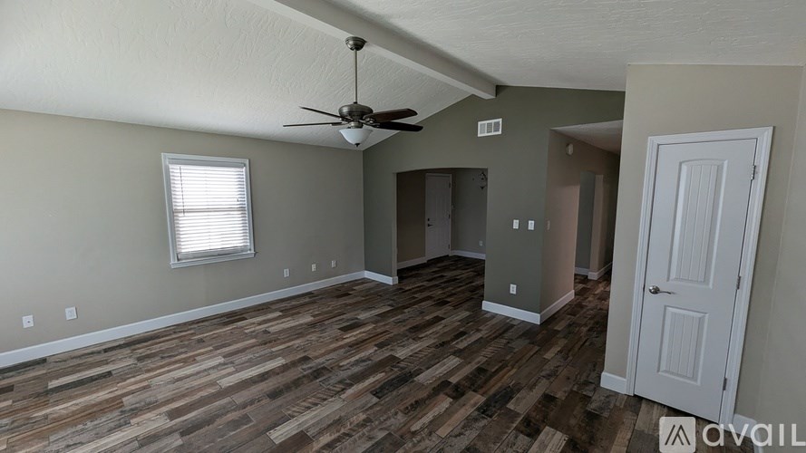 A room with a ceiling fan and wooden flooring.