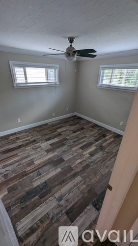 A room with a fan and two windows.