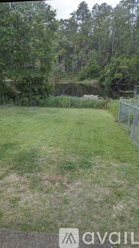 A grassy area with a lake and trees in the background.