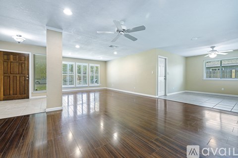 A spacious room with wooden floors and a ceiling fan.