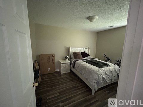 A bedroom with a bed, nightstand, and a cardboard box on the floor.