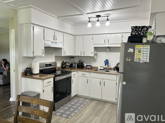 A kitchen with white cabinets and a black fridge.