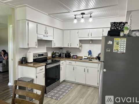 A kitchen with white cabinets and a black fridge.