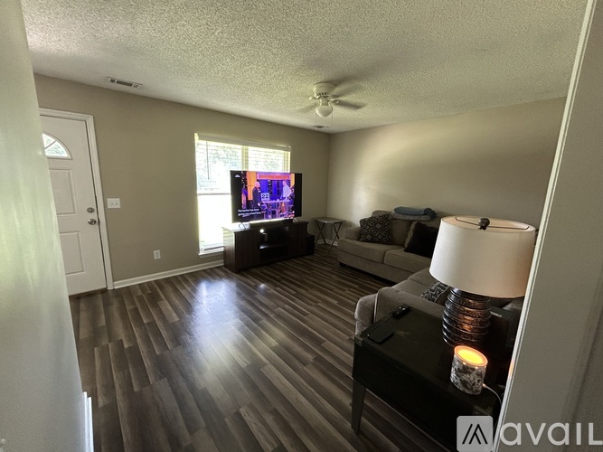 A living room with a television, couch, and a table with a lit candle on it.