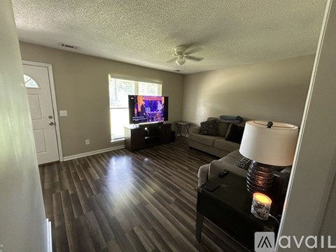 A living room with a television, couch, and a table with a lit candle on it.