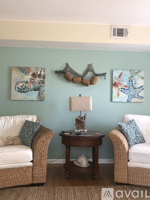 A living room with two chairs, a table, and two paintings on the wall.
