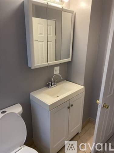 A white bathroom with a toilet, sink and mirror.