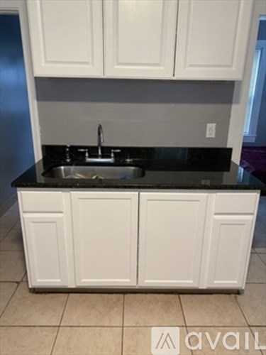A kitchen with white cabinets and a black countertop.
