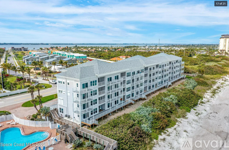 A large white building with a pool in front of it.