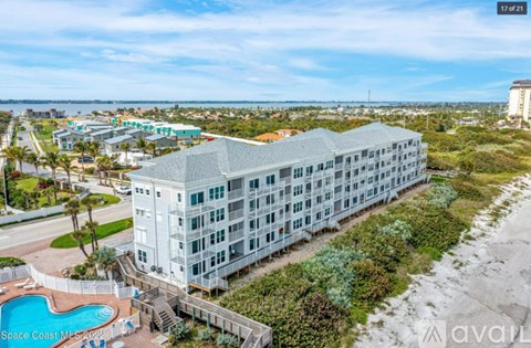 A large white building with a pool in front of it.