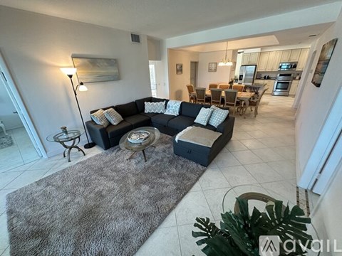 A living room with a grey rug and a black couch.