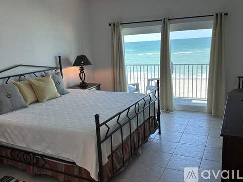 A bedroom with a large bed and a view of the beach.