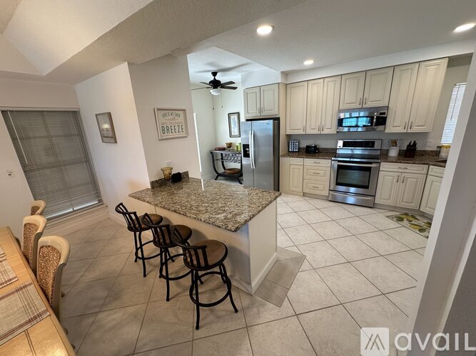 A kitchen with a granite countertop and a dining table with chairs.