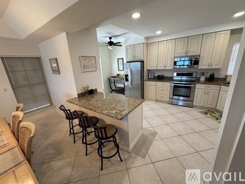 A kitchen with a granite countertop and a dining table with chairs.