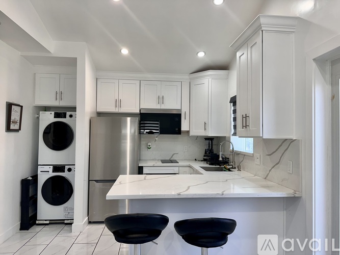 A modern kitchen with white cabinets and a marble countertop.