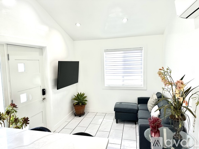 A living room with a black couch and a flat screen TV mounted on the wall.