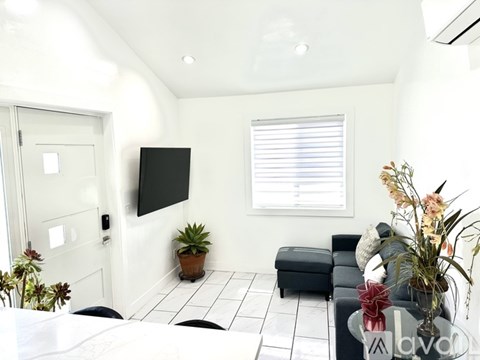 A living room with a black couch and a flat screen TV mounted on the wall.
