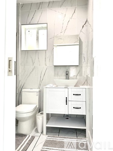 A white bathroom with a toilet, sink, and mirror.