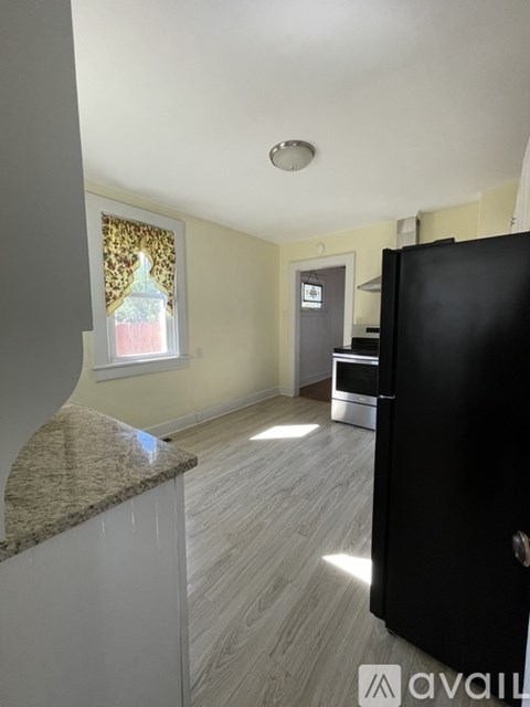 A kitchen with a black refrigerator and a marble countertop.