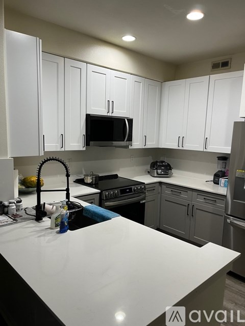 A kitchen with white cabinets and a black counter top.