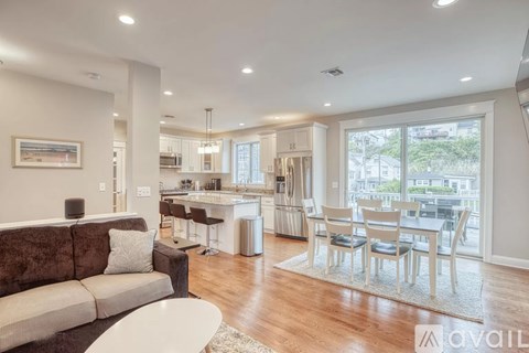 A modern living room with a brown couch and a dining table with chairs.
