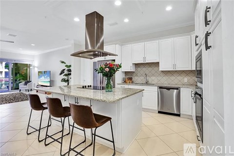 A kitchen with white cabinets and a marble island.