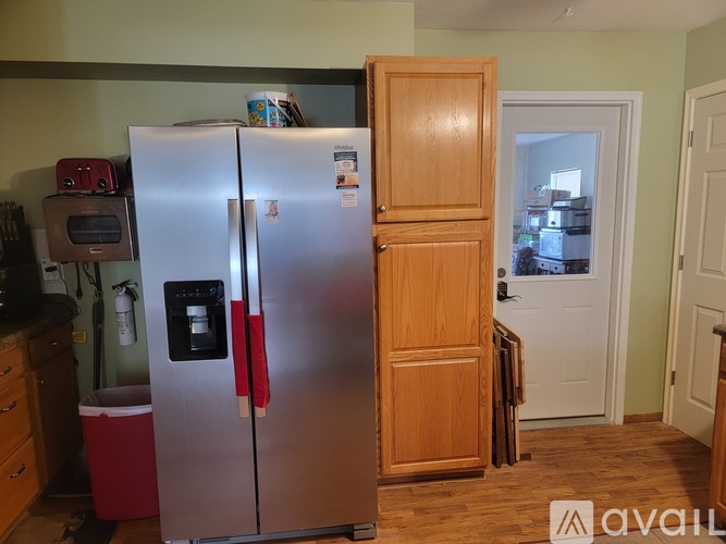 A silver refrigerator with a red handle stands in a kitchen.