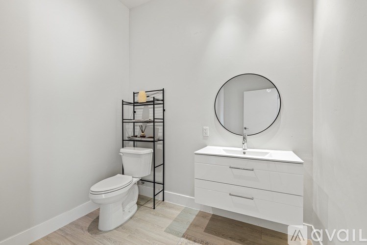 A white bathroom with a toilet, sink, and a mirror.