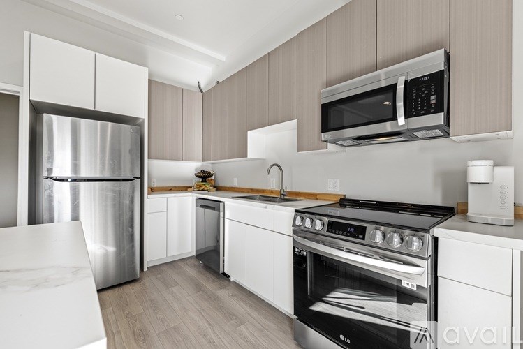 A kitchen with a stainless steel refrigerator, white cabinets, and a black stove top oven.