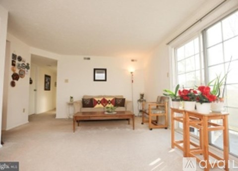 A living room with a couch, a chair, and a table with flowers.