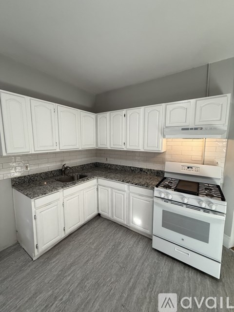 A kitchen with white cabinets and a granite countertop.