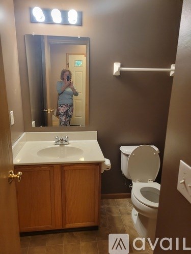 A woman is taking a selfie in a bathroom with a sink, toilet and mirror.