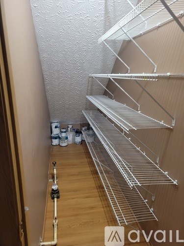 A long hallway with a pipe on the floor and shelves on the wall.