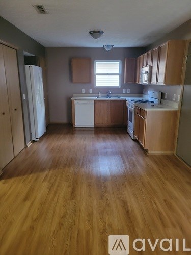 A kitchen with wooden floors and white appliances.