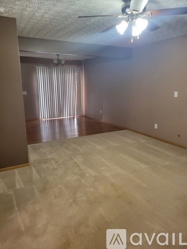 A room with a carpeted floor and a ceiling fan.