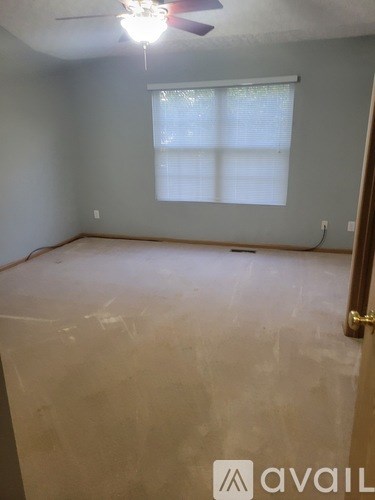 A room with a ceiling fan and a window with blinds.