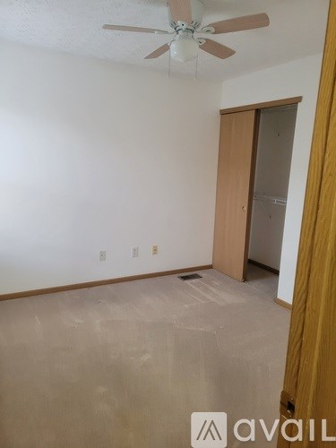 A room with a ceiling fan and a door.