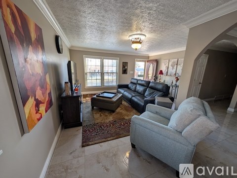 A living room with a grey couch and a large painting on the wall.